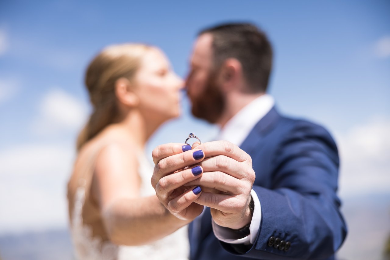 Their hands with the rings, the couple soft behind