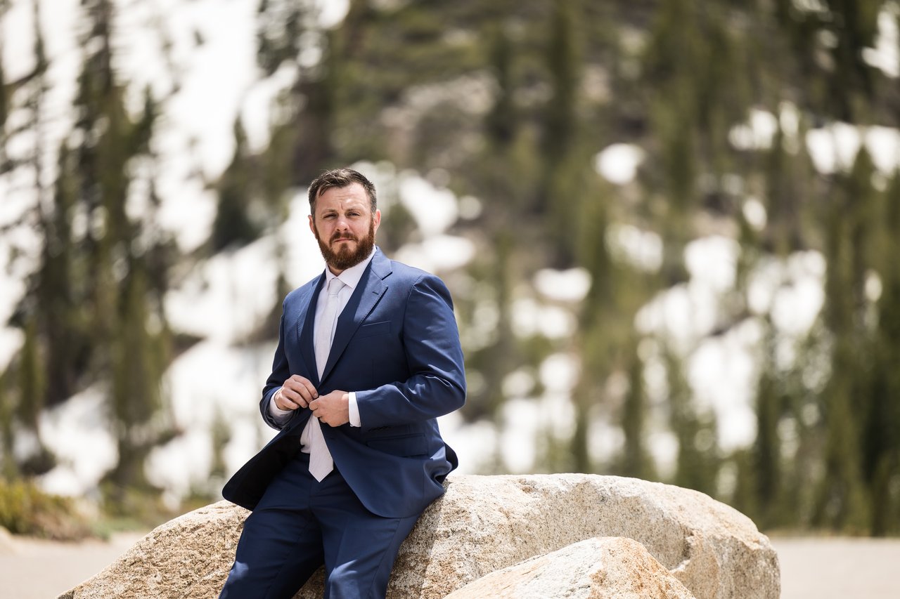 Robert on a boulder with snowy pines behind him