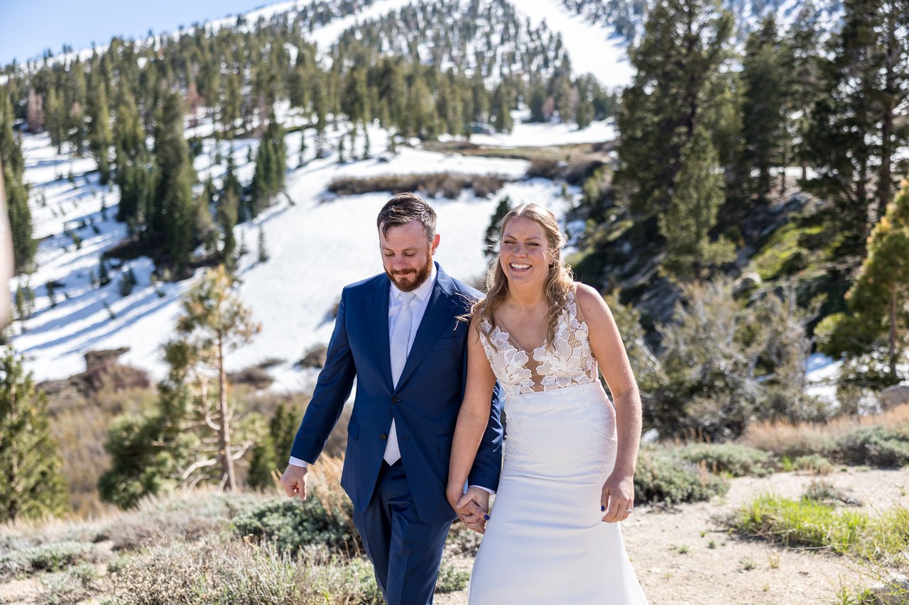 Ali and Robert walk with the snowy ski slopes behind them