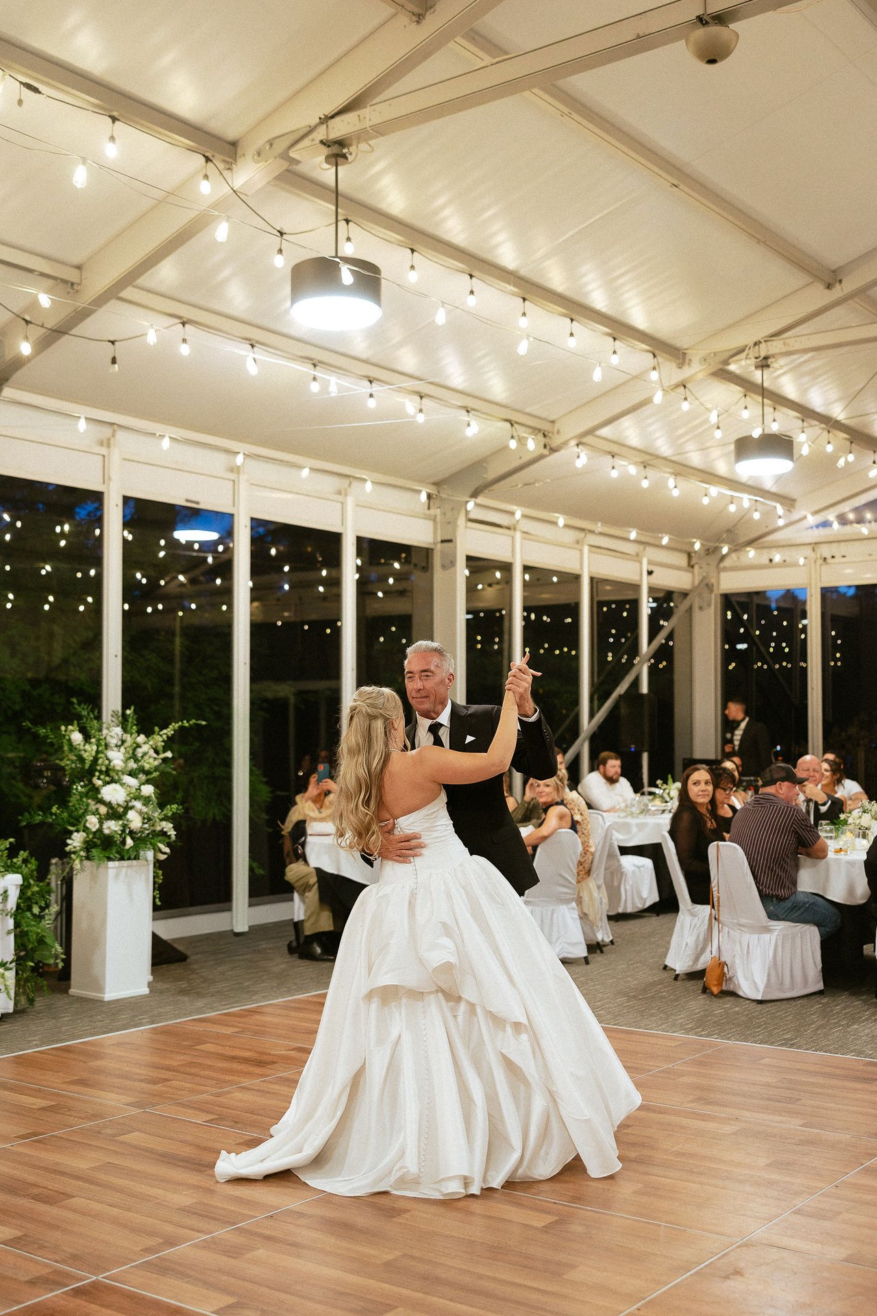 Ally dances with her dad under the string lights in the tent