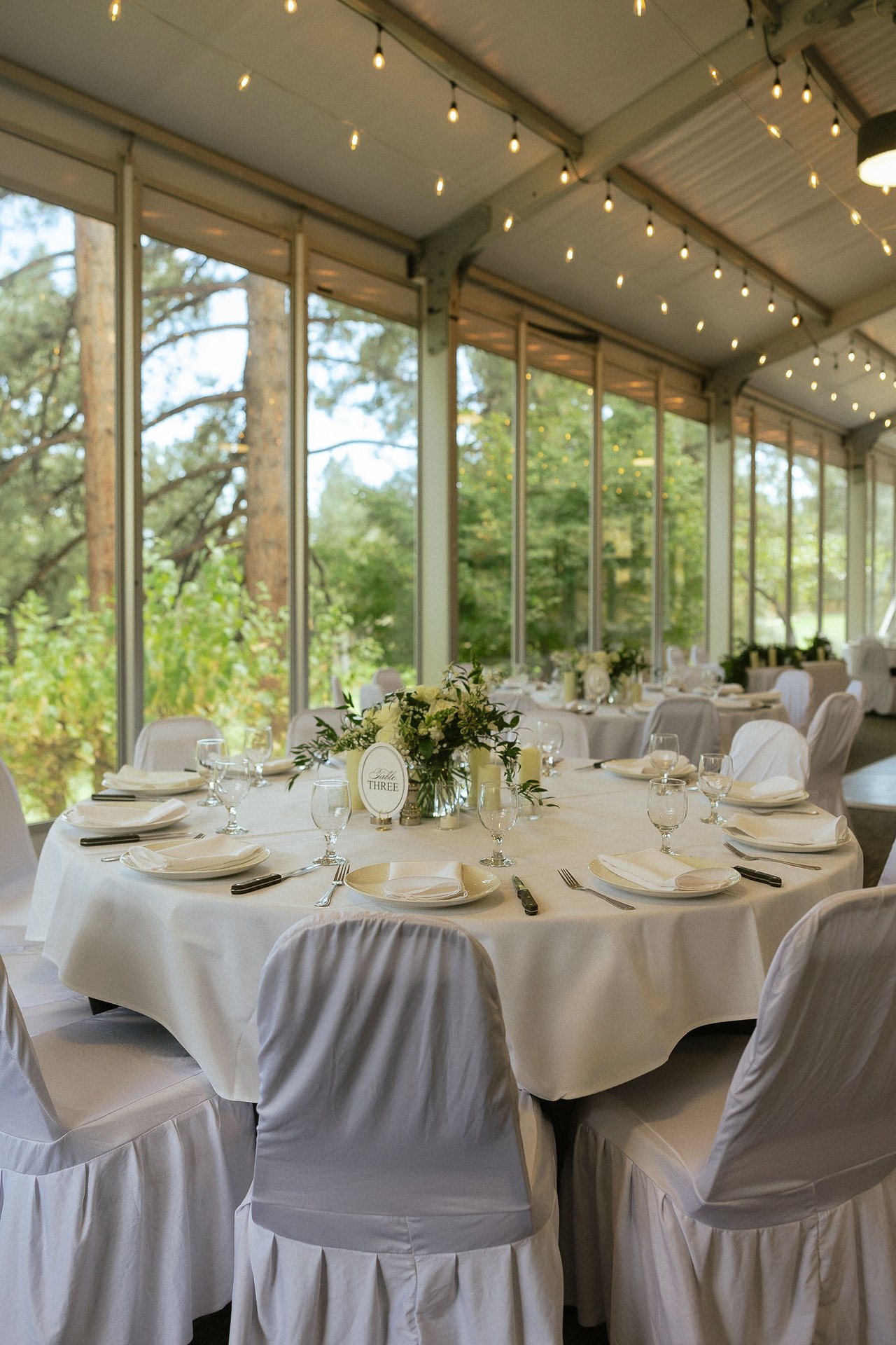 A closer look at the set tables in the tent, pines outside the windows