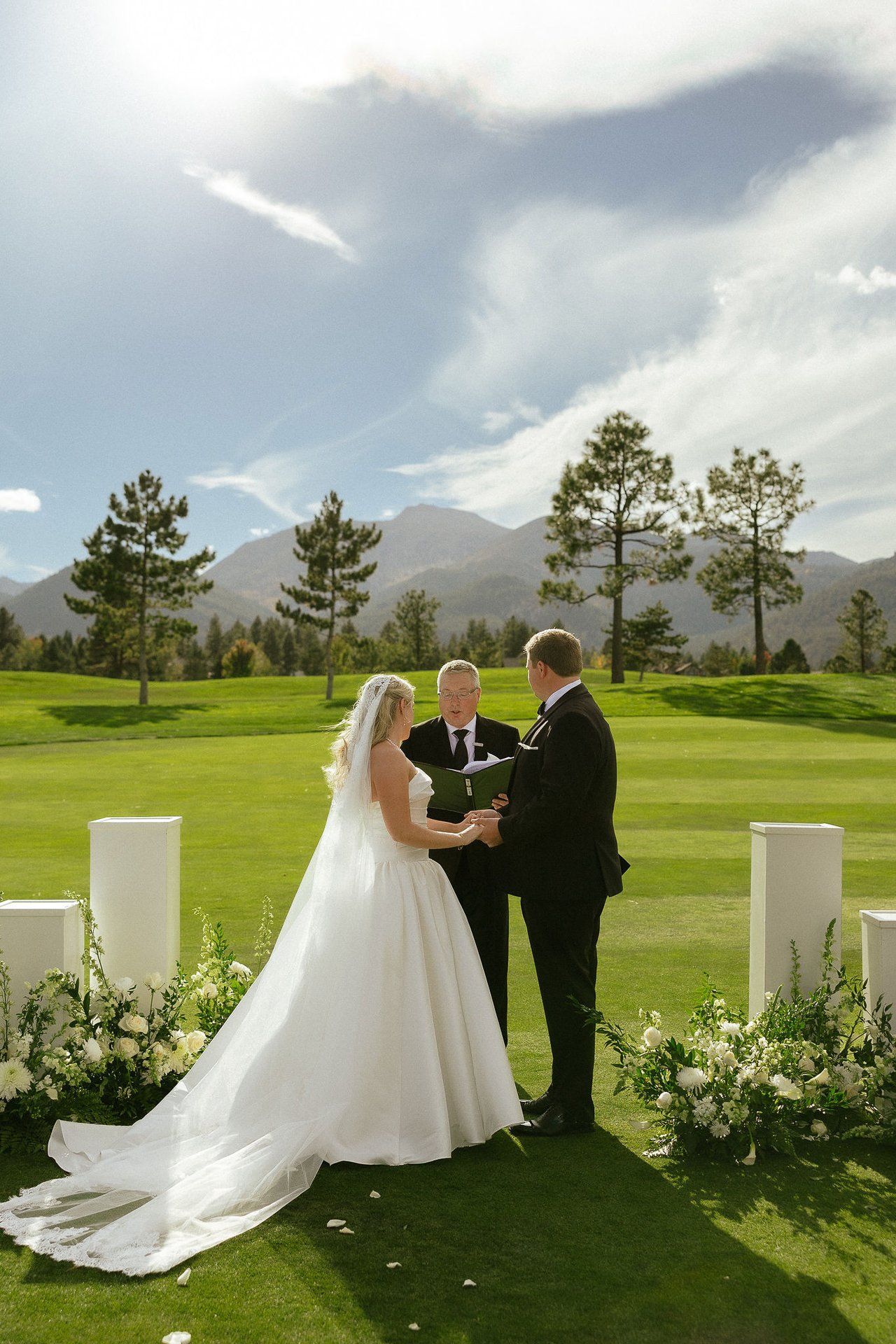 Ally and Drew say their vows on the fairway with their guests seated and the mountains behind them