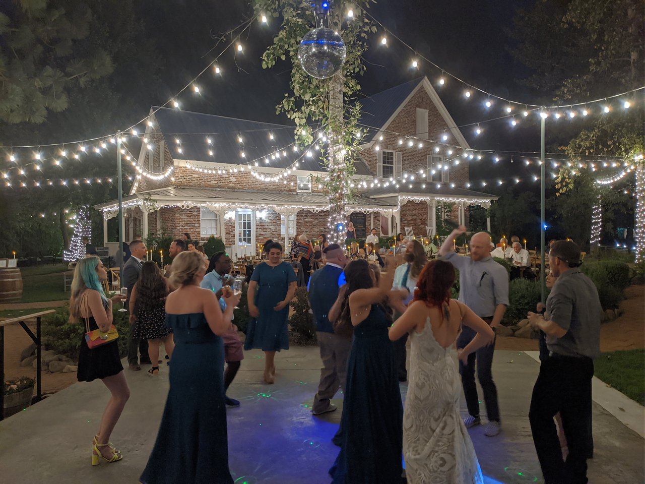 Amanda dances in her wedding gown with friends under the string lights