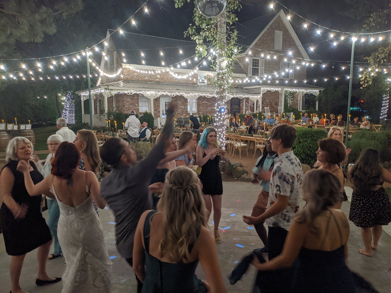 Amanda dancing with guests under the string lights at night