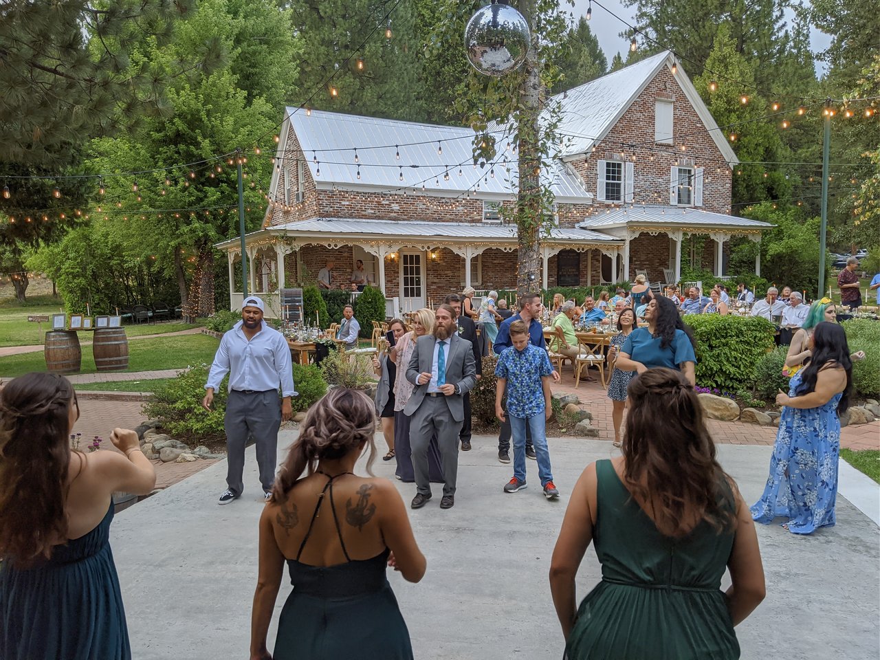 Bridesmaids in green dance as guests join them on the patio