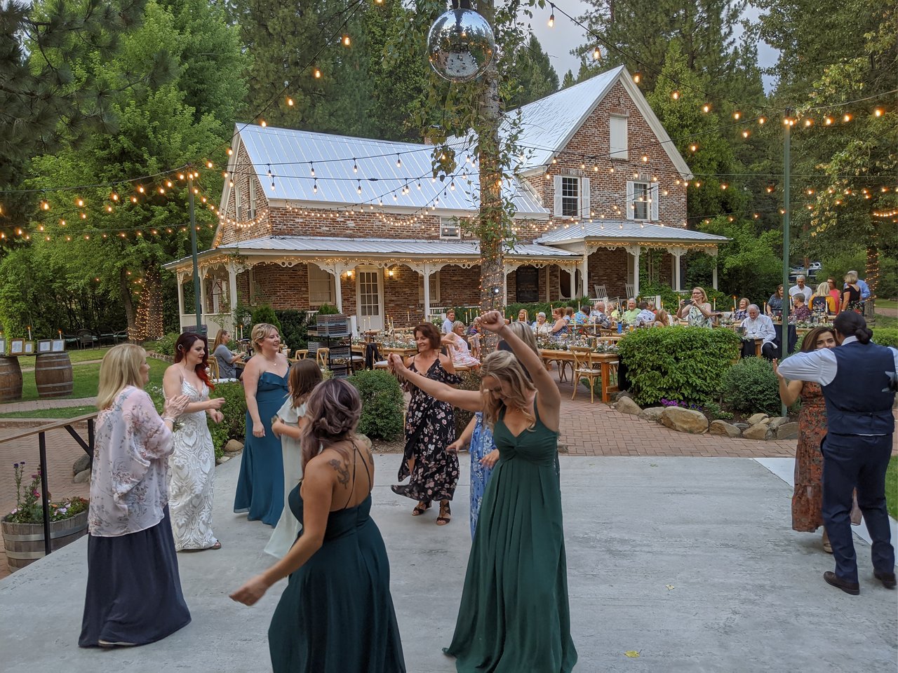 Amanda and her bridesmaids dance under the string lights in the late afternoon