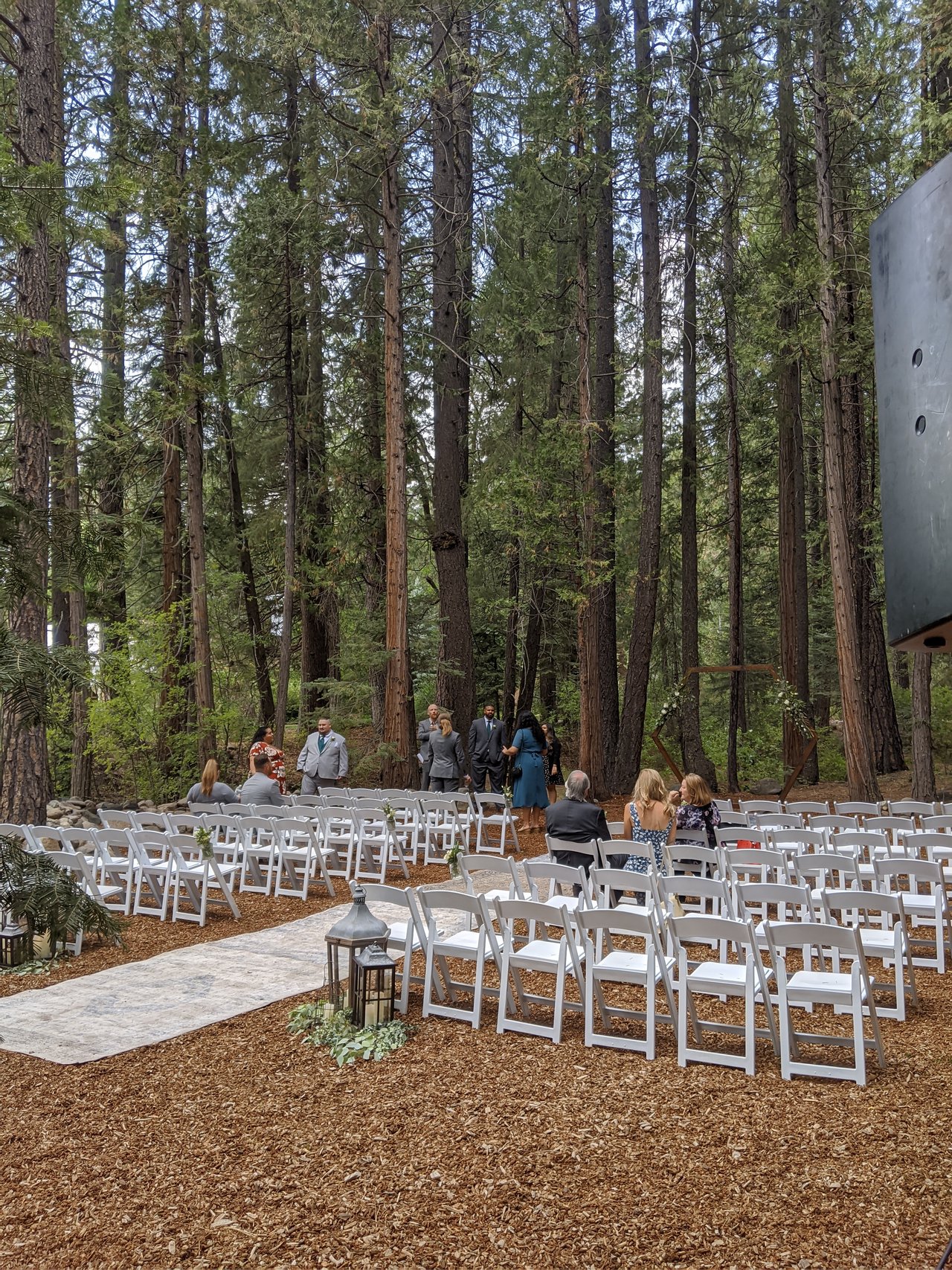 White chairs line the aisle for the ceremony in the pines before guests arrive