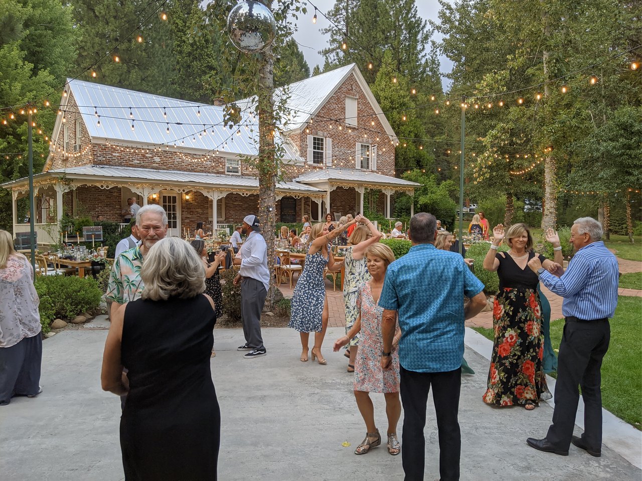 Couples dancing on the patio in front of the brick house at Twenty Mile House