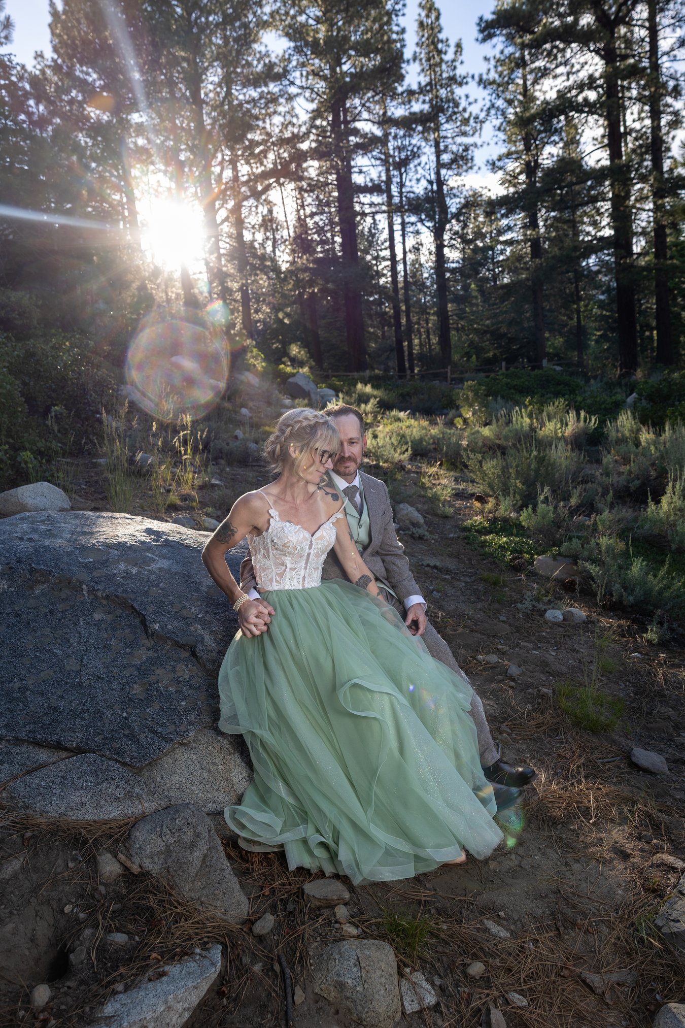 Amy and Justin walking a rocky forest trail as the sun breaks through the pines