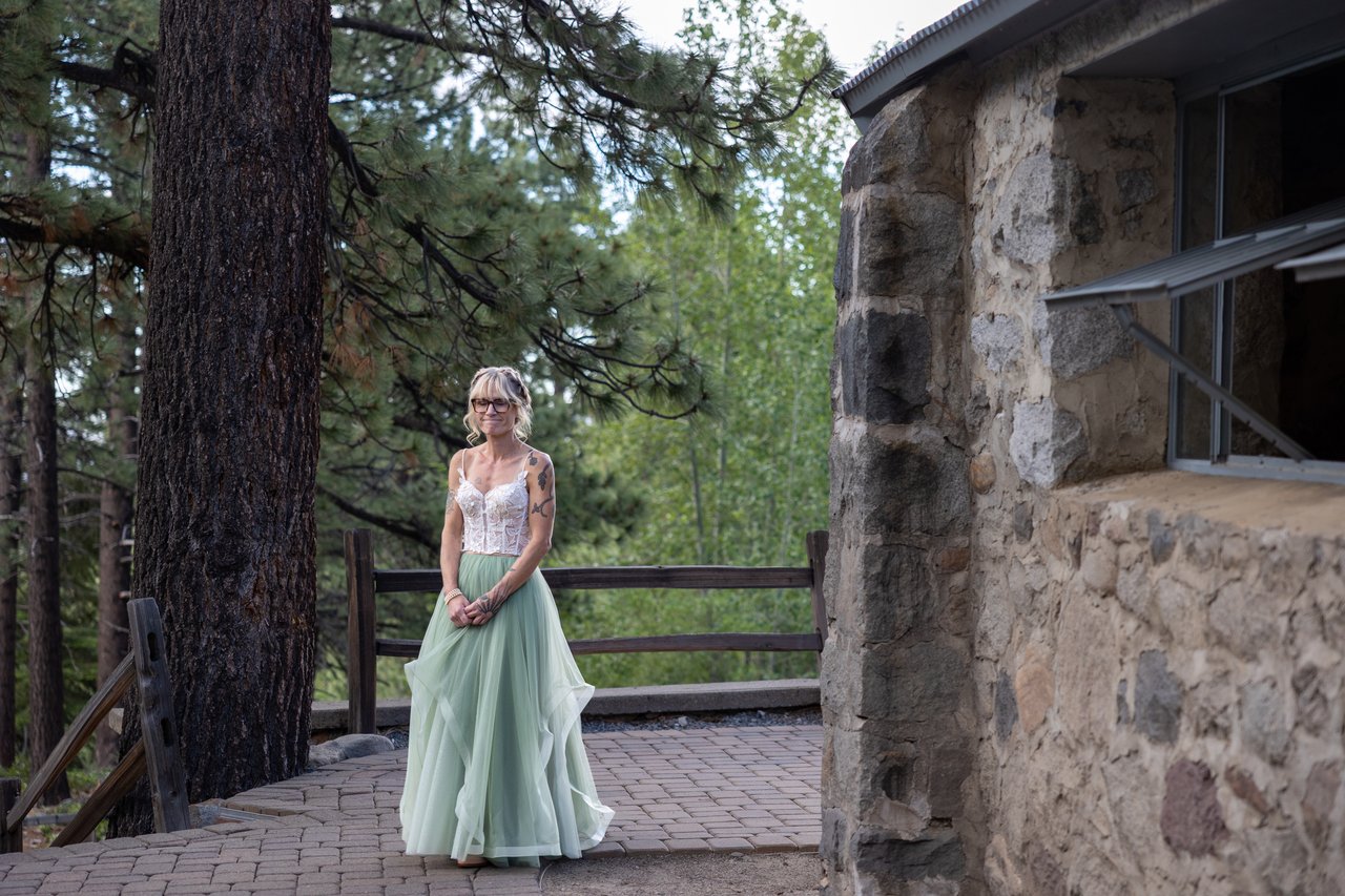 Amy waits at the top of the aisle beside the stone building