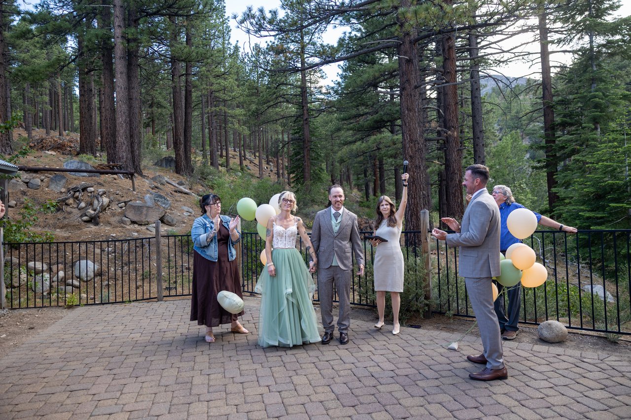 Amy and Justin raise their arms as newlyweds while their guests cheer