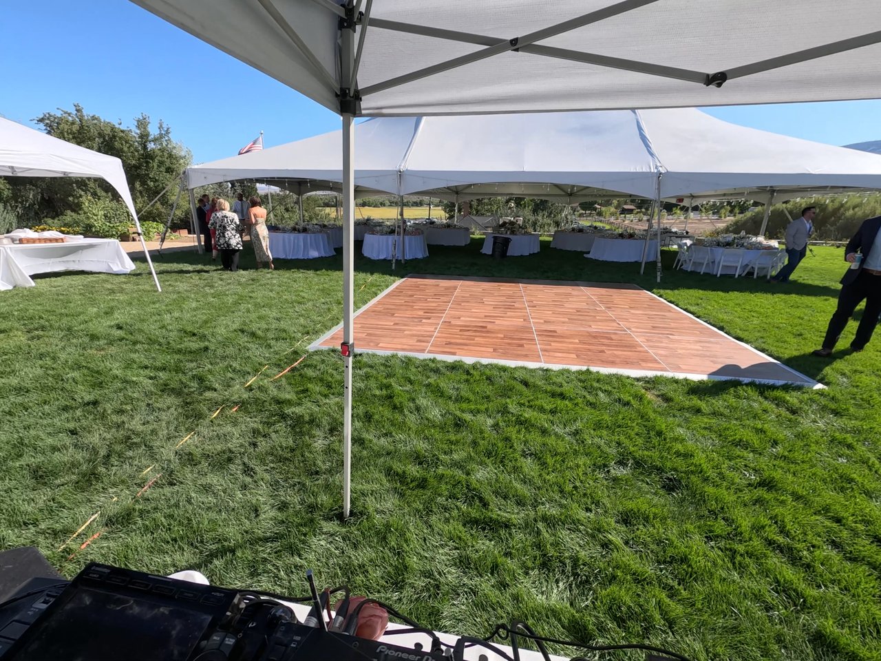 The wooden dance floor laid out on the lawn beside the white tents before the guests arrive