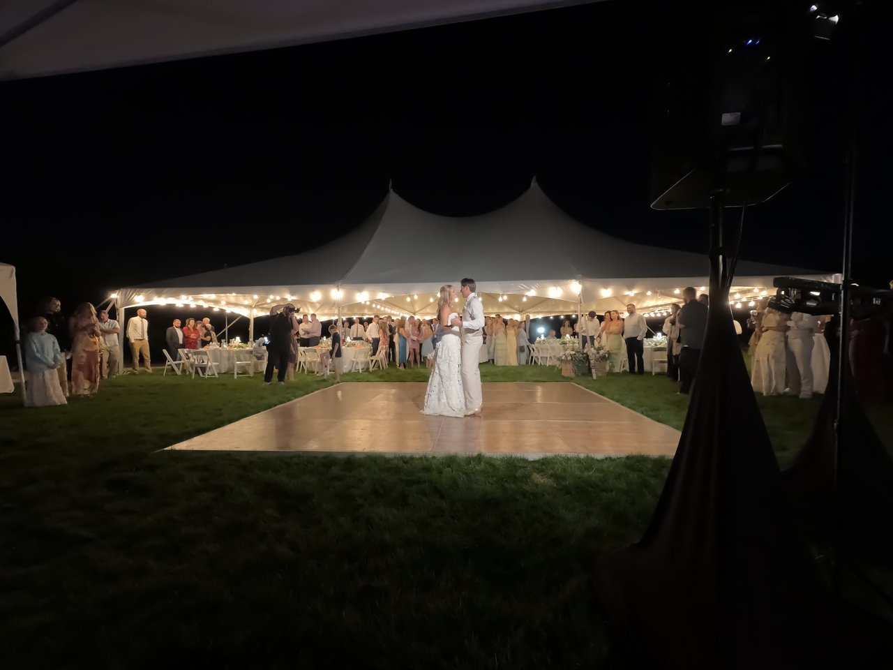 Anabella and Wyatt share their first dance on the lawn dance floor as guests gather around the tent