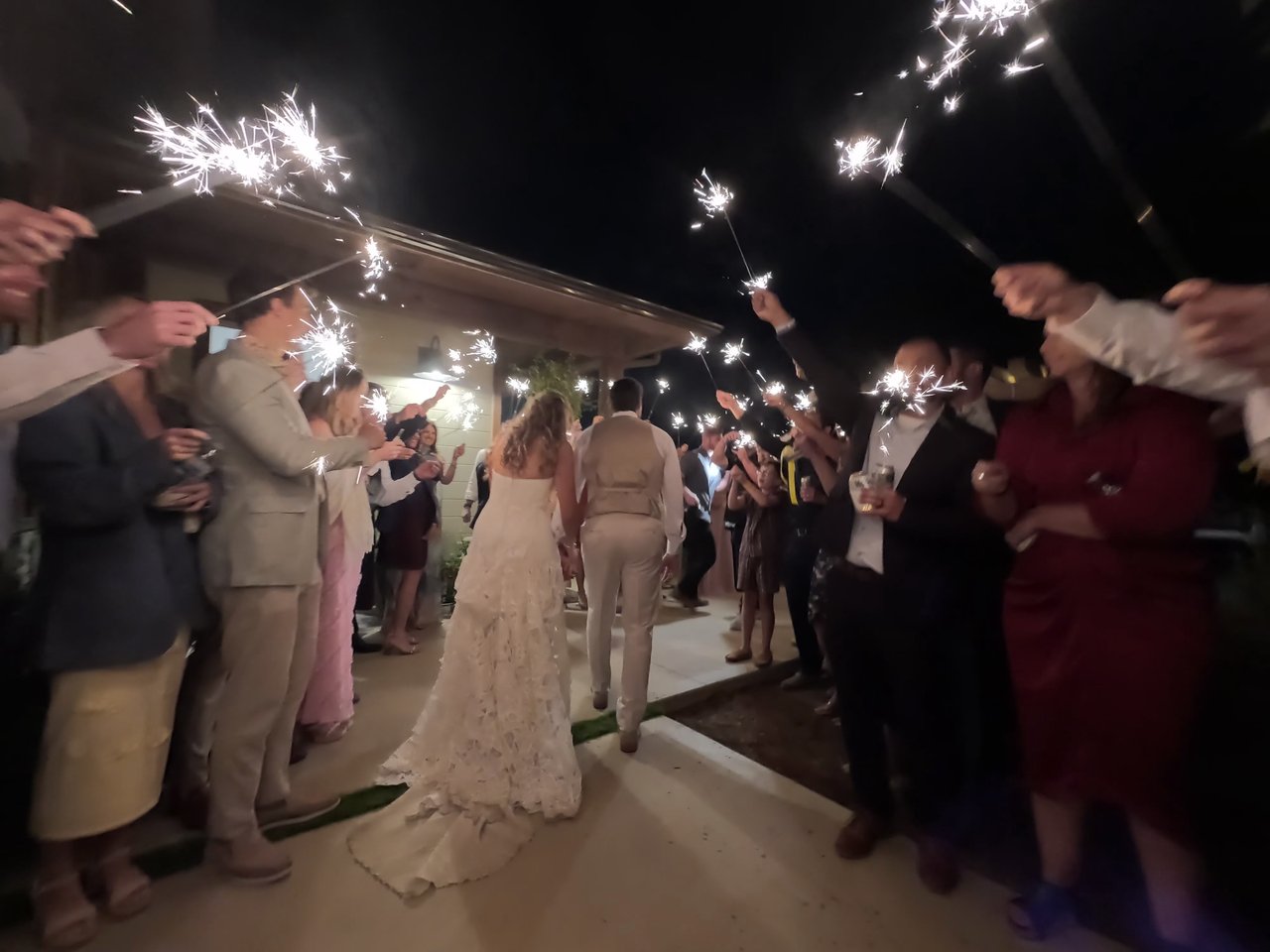 Anabella and Wyatt walk through a tunnel of sparklers held by their guests
