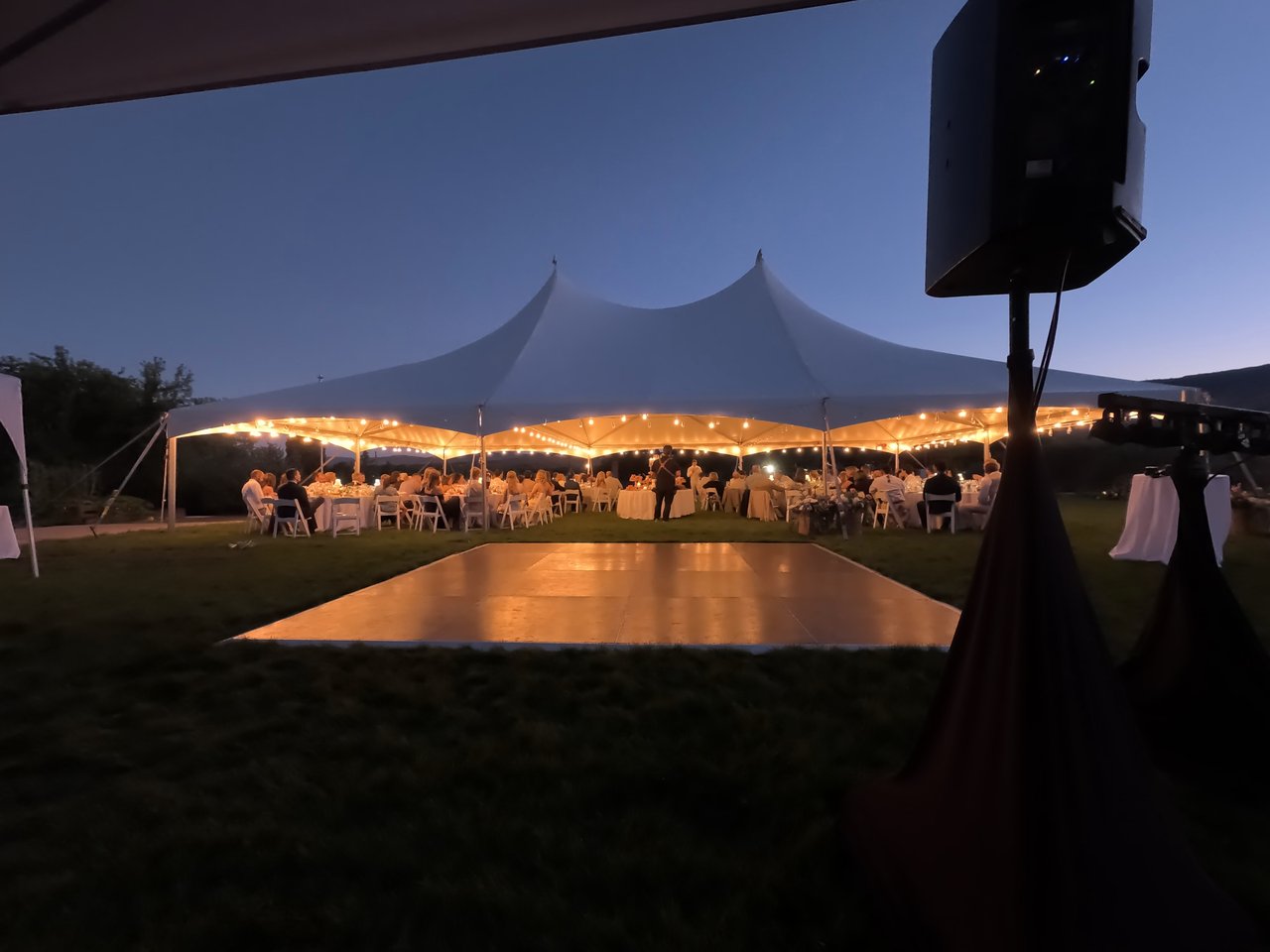 The big white tent glows with string lights at dusk as guests sit down to dinner
