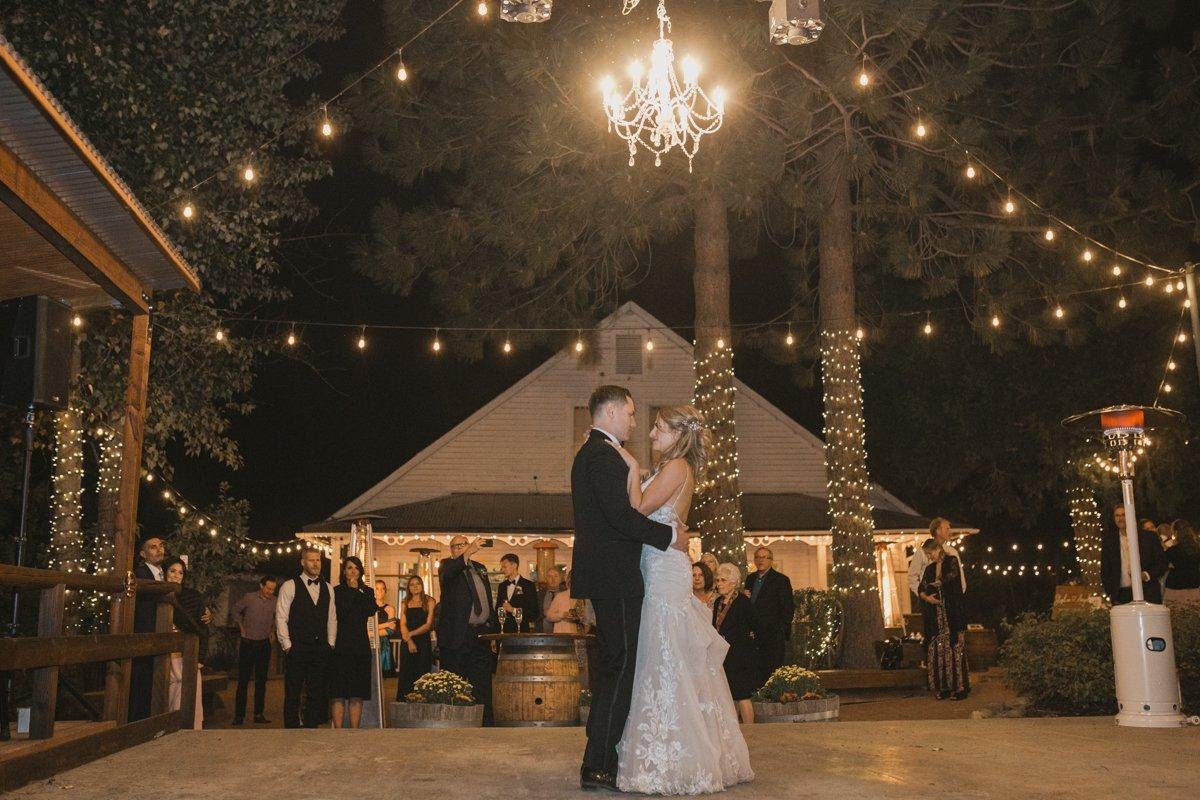 Angela and Stephen share their first dance under the chandelier and string lights as guests watch, photo by Composing Reality Photography