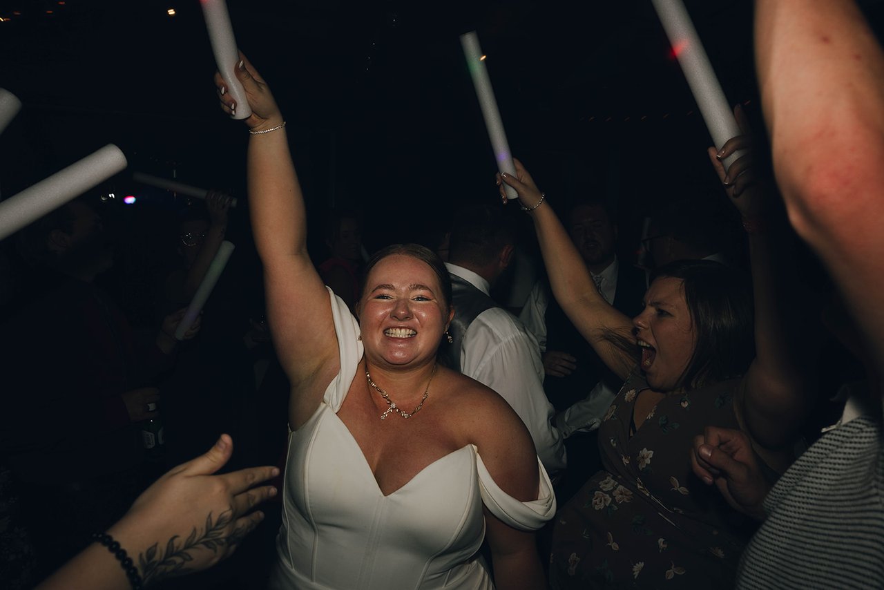 Autumn laughs with a foam glow stick raised over her head on the dance floor
