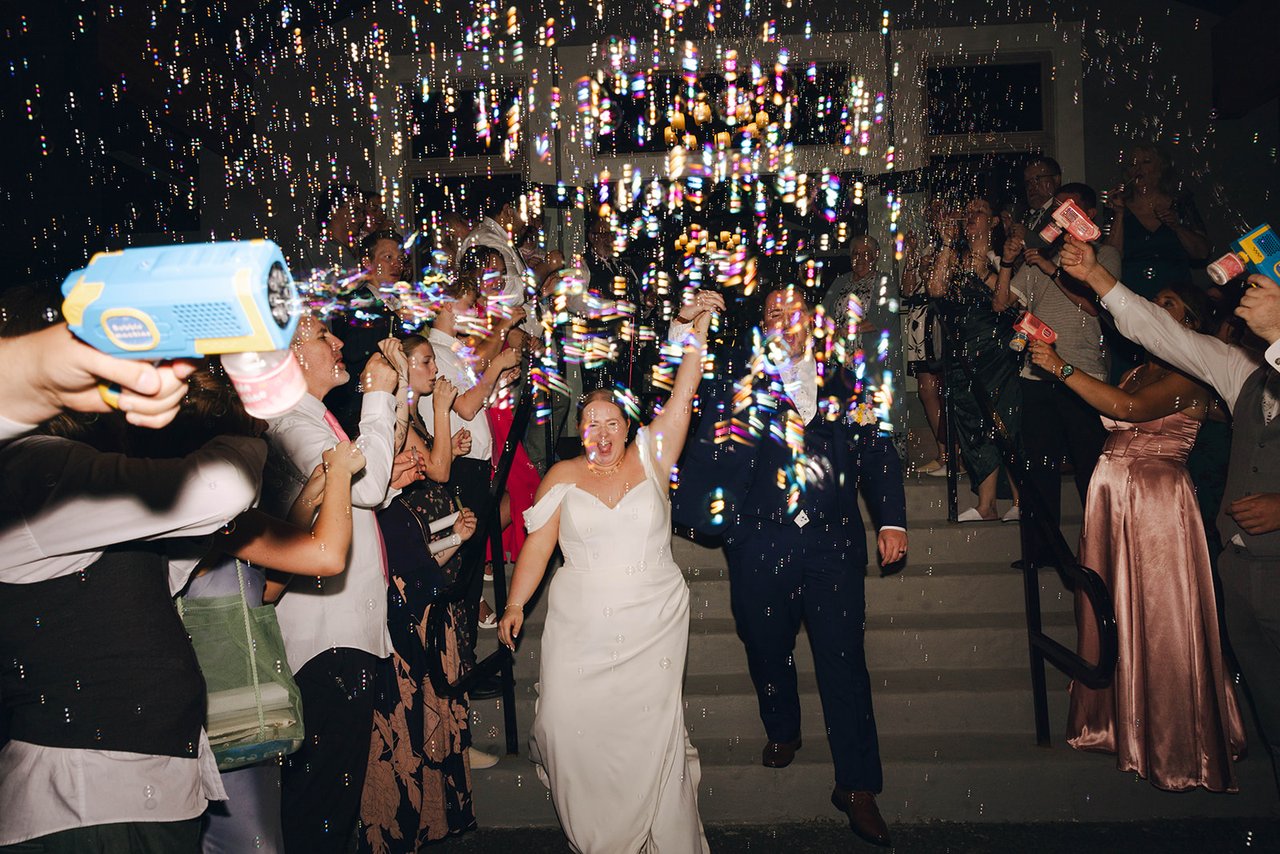 Autumn and Peter come down the steps through a cloud of bubbles from their guests