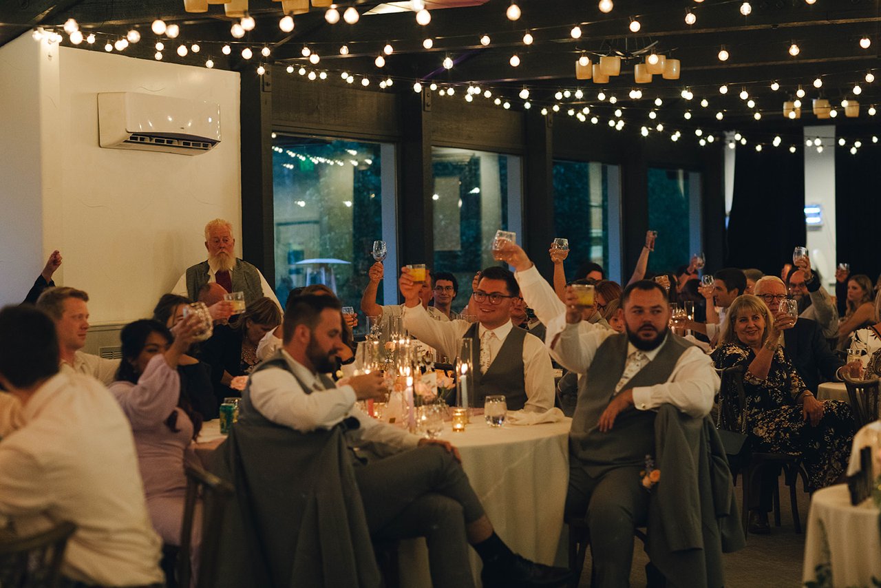 Guests at the tables raise their glasses and cheer during a toast