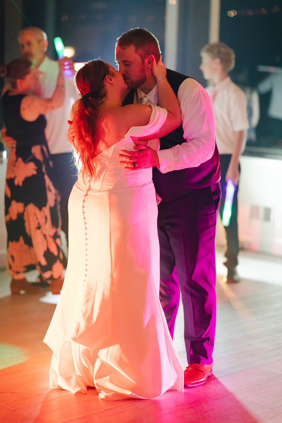 Autumn and Peter kiss on the dance floor, lit red and magenta by the dance lights