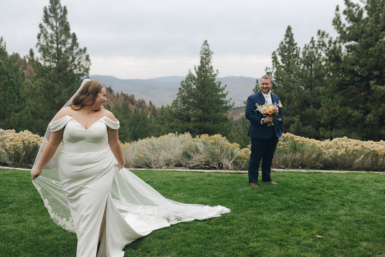 Autumn lifts her train on the lawn and looks back at Peter, who holds her bouquet
