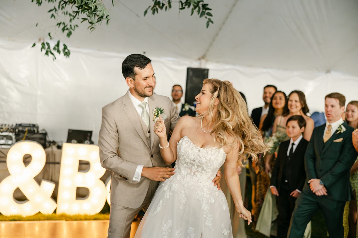 Britt and Chris share a laugh beside their glowing marquee letters on the dance floor
