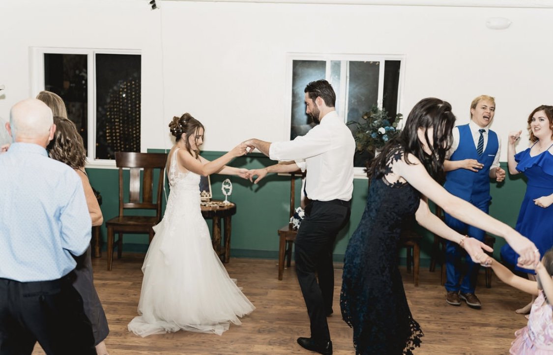 Caitlyn and her guests dance hand in hand in a line across the hall floor