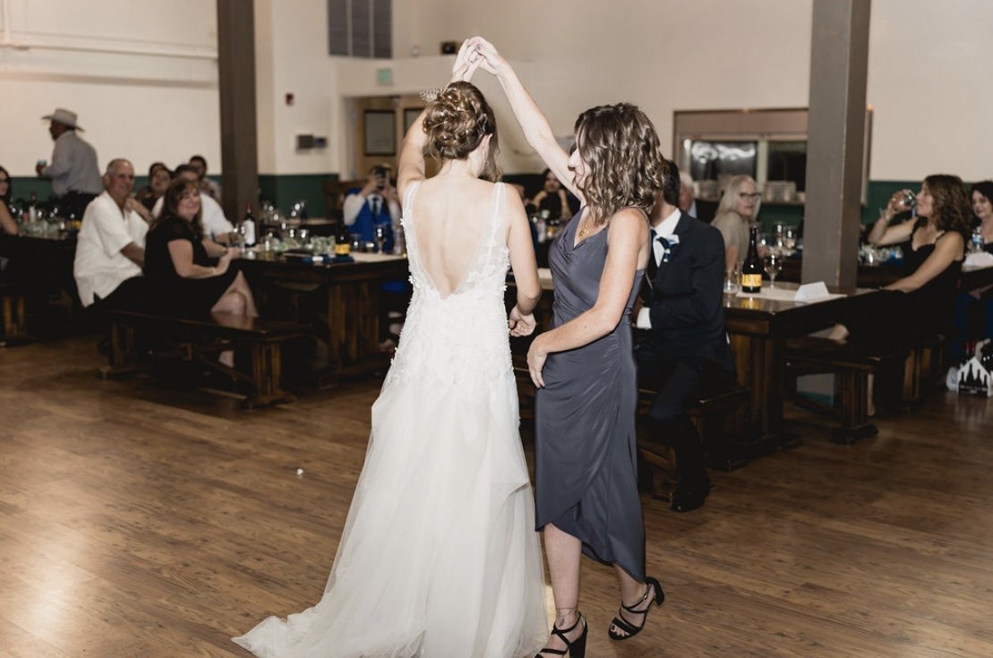 Caitlyn twirls with a friend on the dance floor while guests watch from the tables