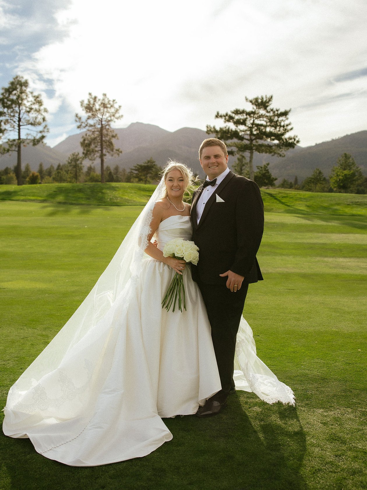Ally holds her white roses beside Drew on the fairway at Montreux, her veil and train across the grass, photo by Photos by Laila