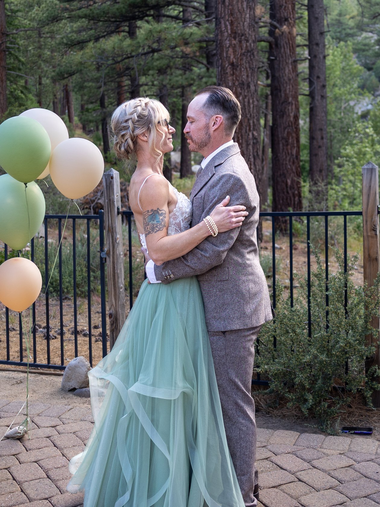 Amy and Justin embracing beside a bunch of balloons on their wedding day