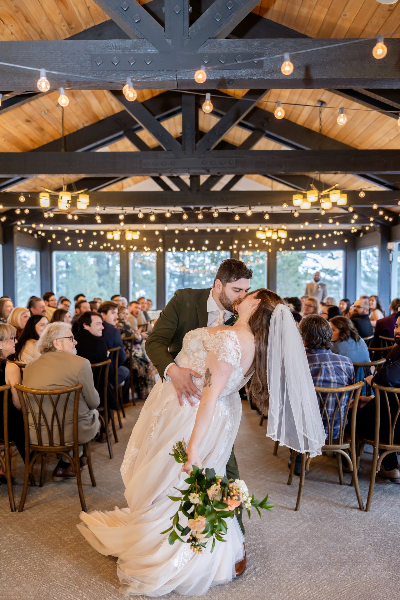 Brandon dips Danielle for a kiss in the aisle under the wood beams