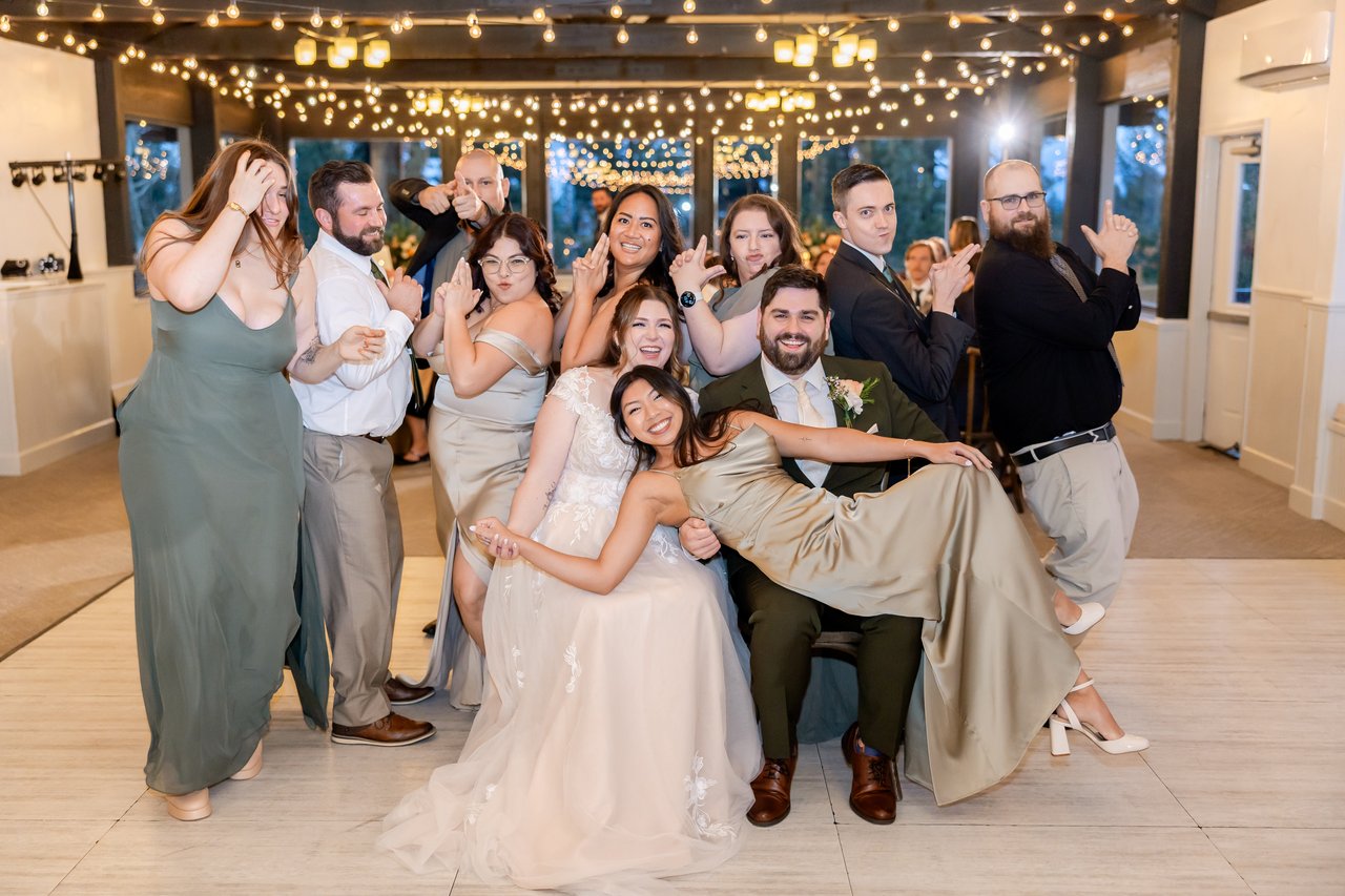 A bridesmaid lies across Danielle and Brandon's laps as the wedding party poses