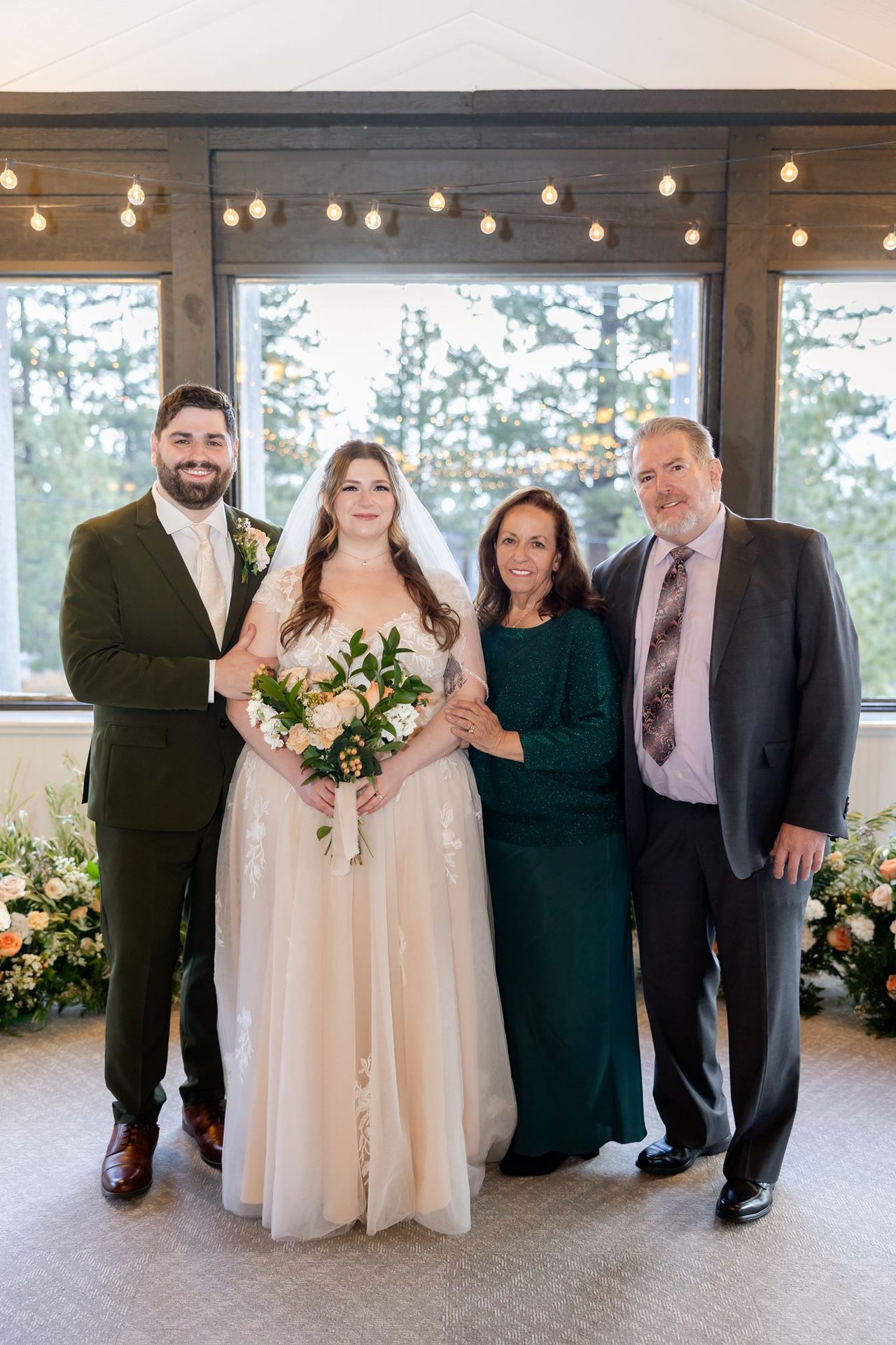 Danielle and Brandon with her parents in front of the ceremony flowers