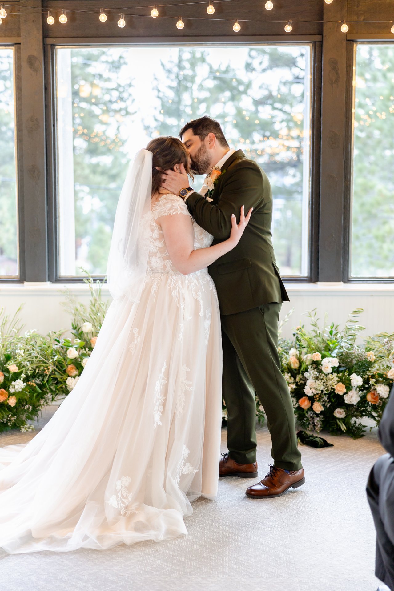 First kiss as husband and wife beside the flowers at the windows