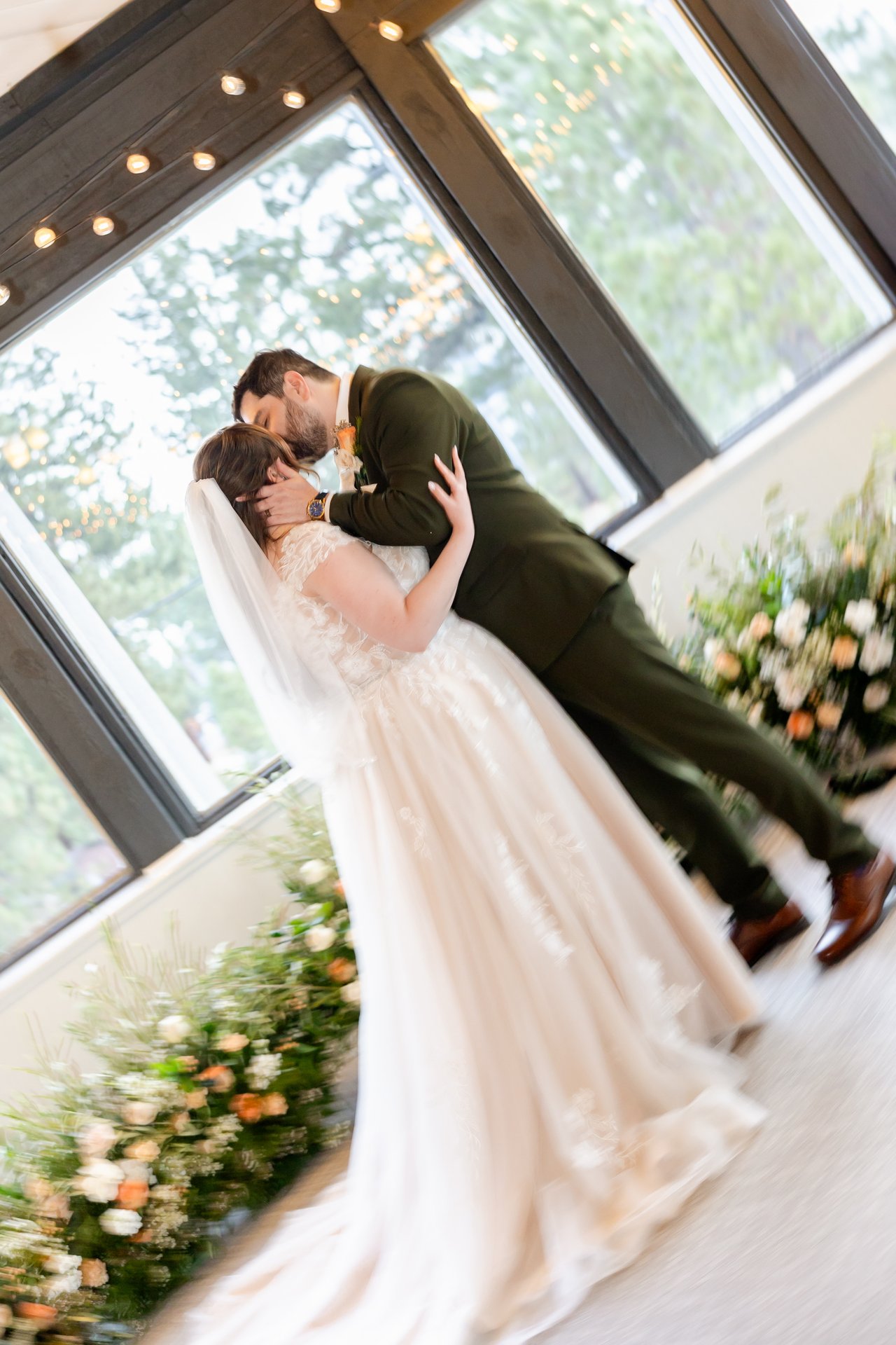 Danielle and Brandon's first kiss beside the flowers at the windows