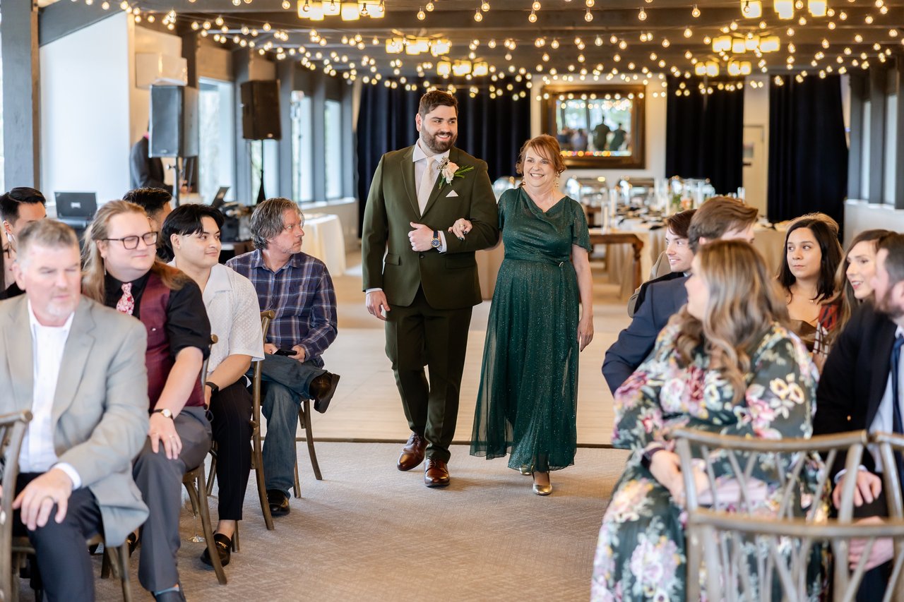 Brandon walks down the aisle with his mom as guests look on