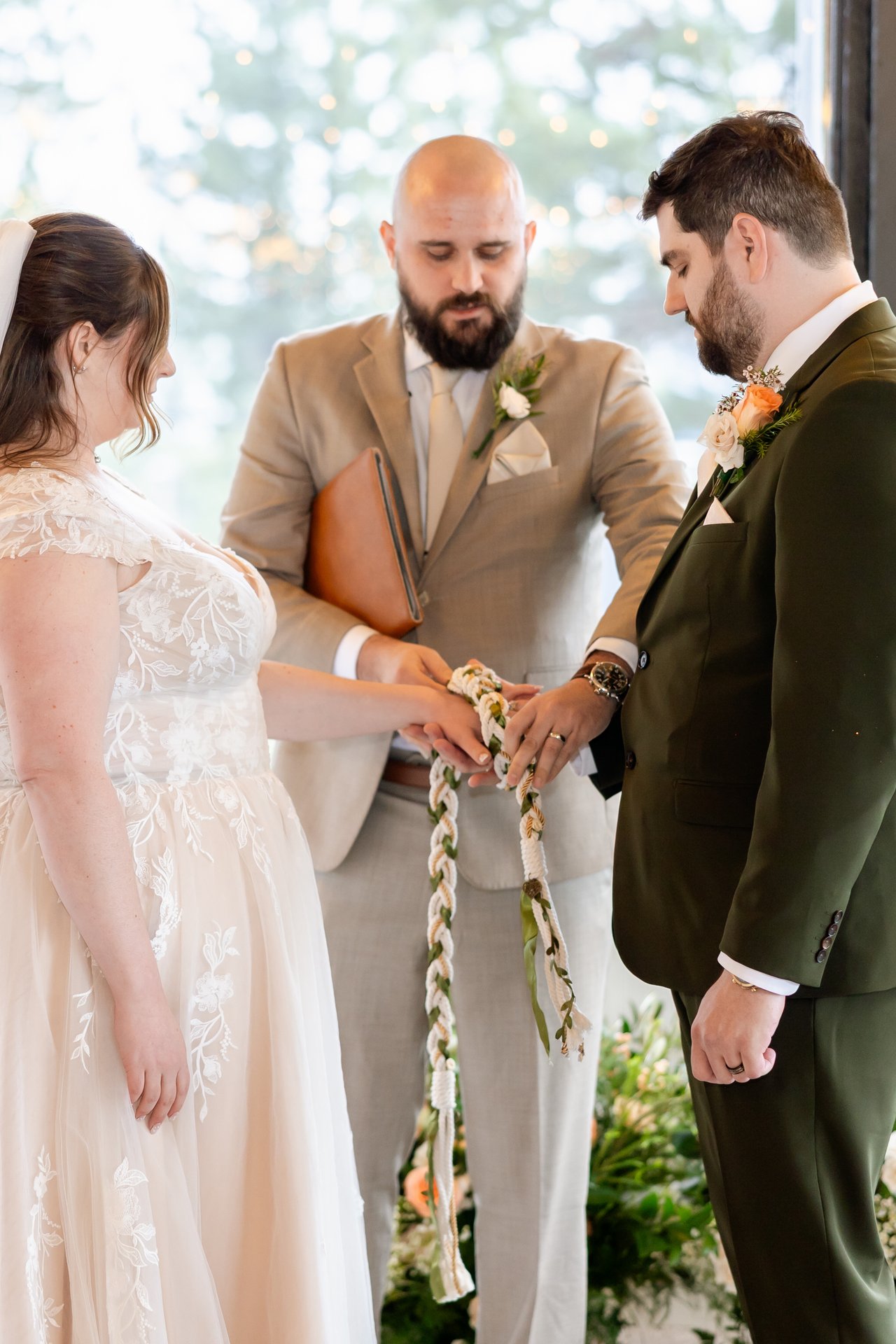 The officiant ties a handfasting cord around Danielle and Brandon's hands