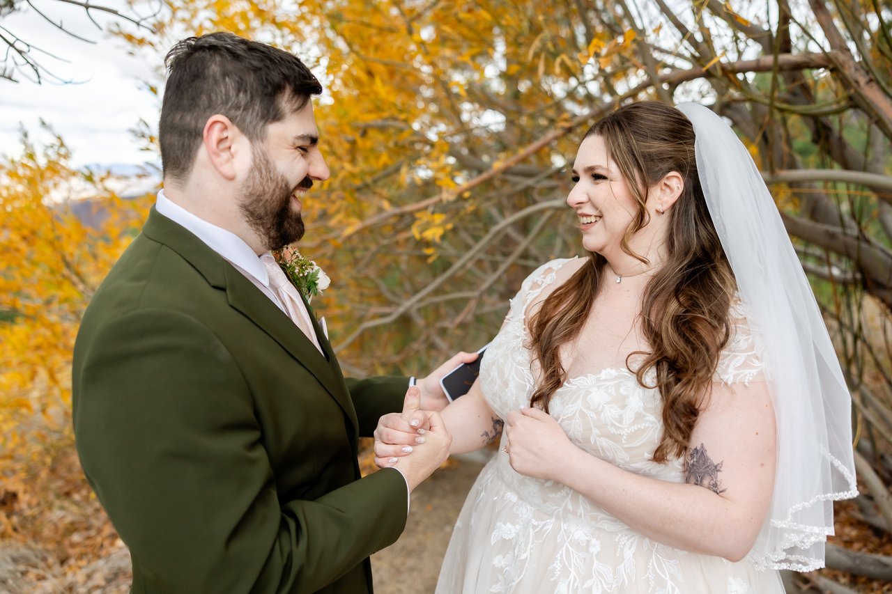 Danielle and Brandon laugh face to face in front of golden aspen branches