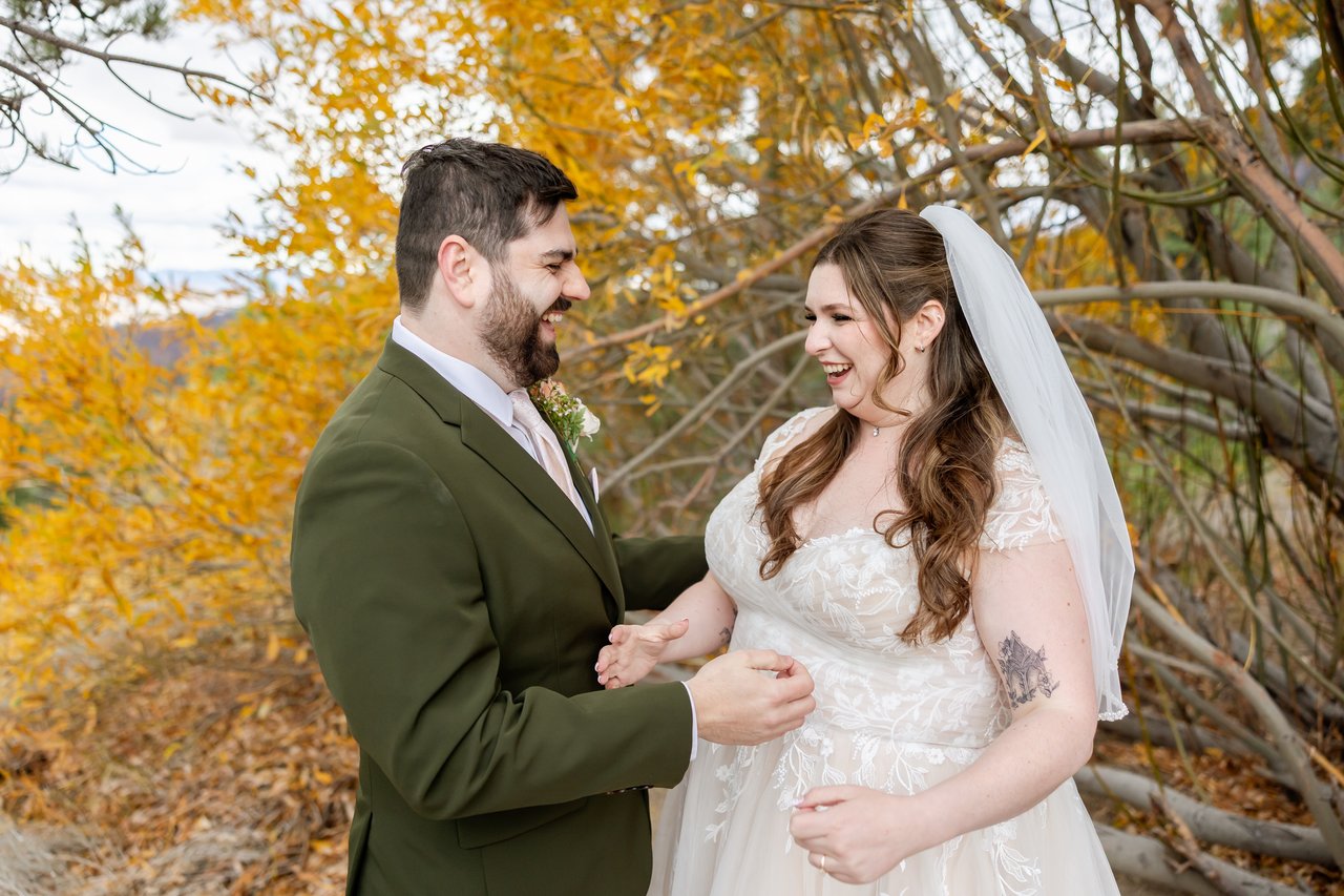 Danielle and Brandon laugh face to face in front of golden aspen branches