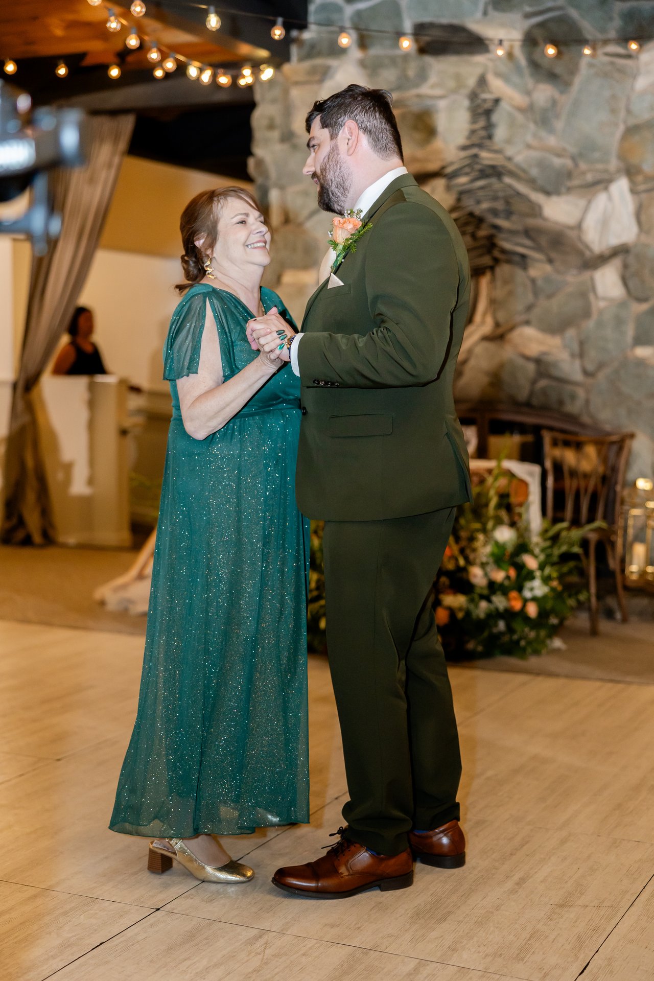 Brandon dances with his mom beside the stone fireplace