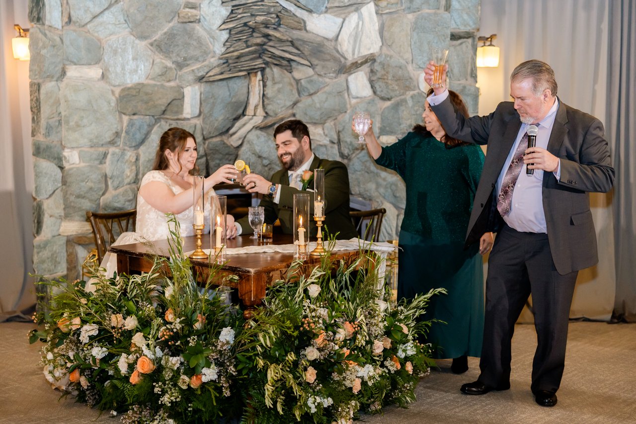 A toast with a raised glass in front of the stone fireplace