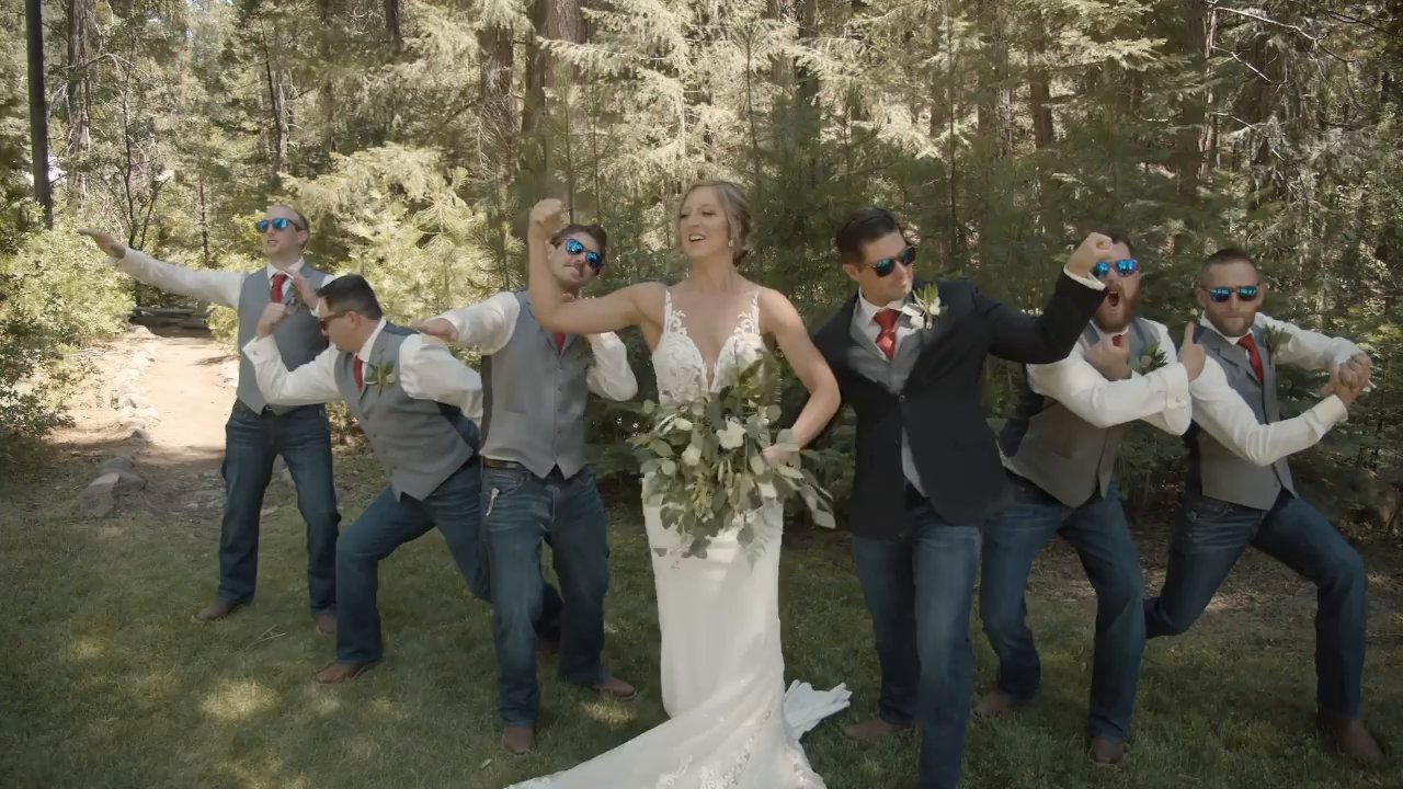 Danielle stands with the groomsmen as they strike a playful pose in the forest.