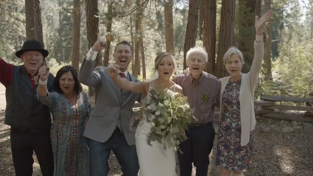 Danielle and Scott cheer with their families in the forest.