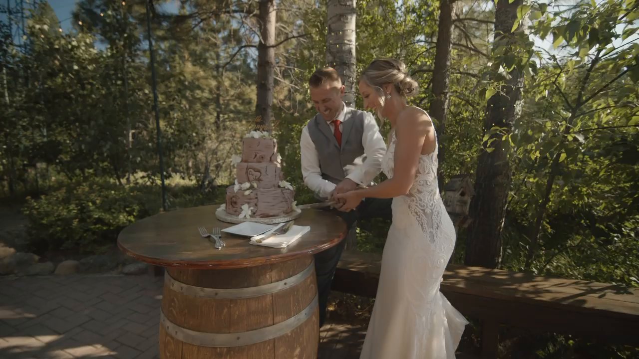 Danielle and Scott cut their cake on a wine barrel table.