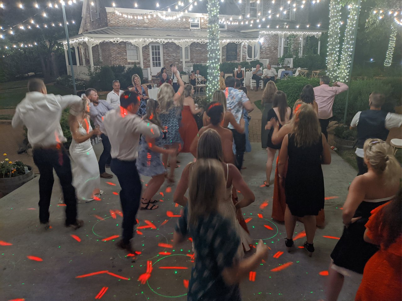 Guests dance under red and green lasers in front of the lit up brick house at Twenty Mile House