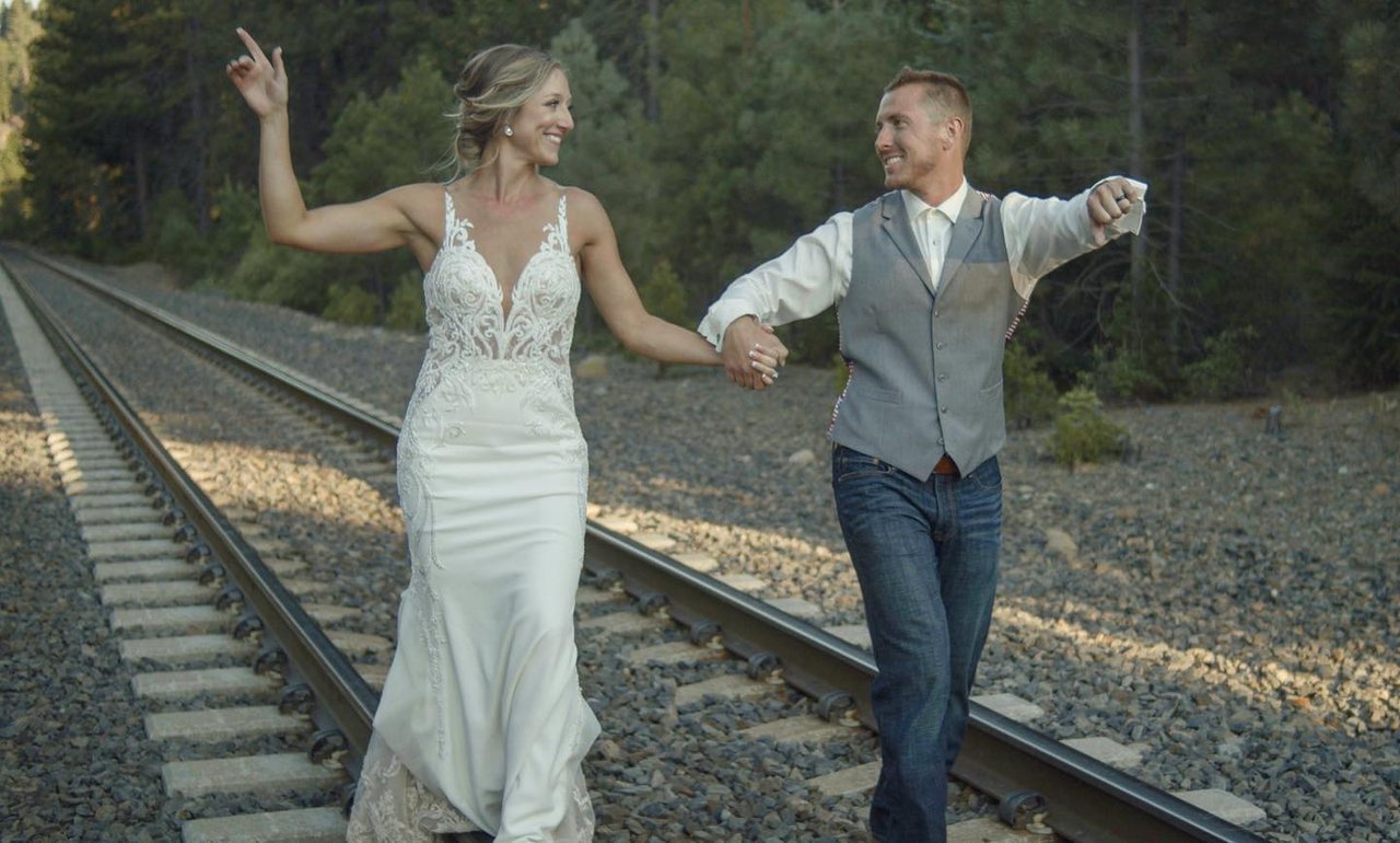 Danielle and Scott dance hand in hand along the railroad tracks beside the forest