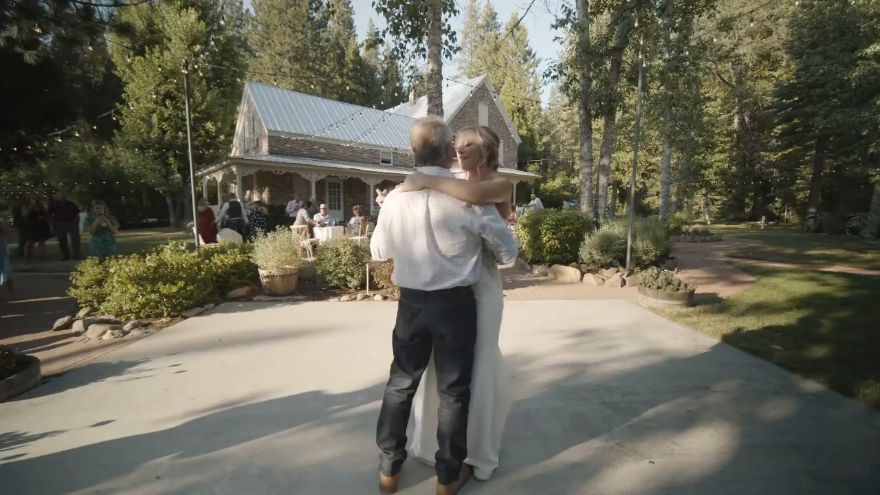 Danielle dances with her dad on the patio in front of the white house.