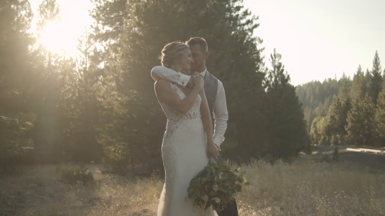 Scott kisses Danielle on the forehead in a field at golden hour.