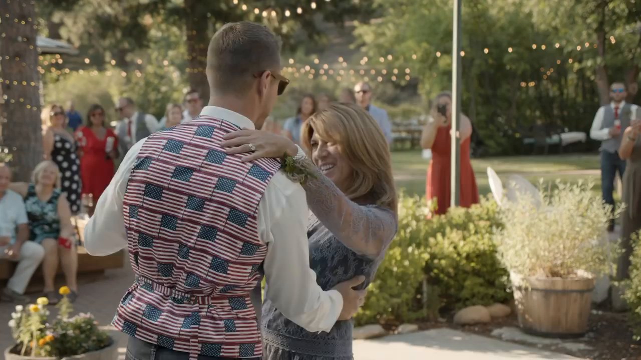 Scott in his flag vest dances with his mom on the patio.