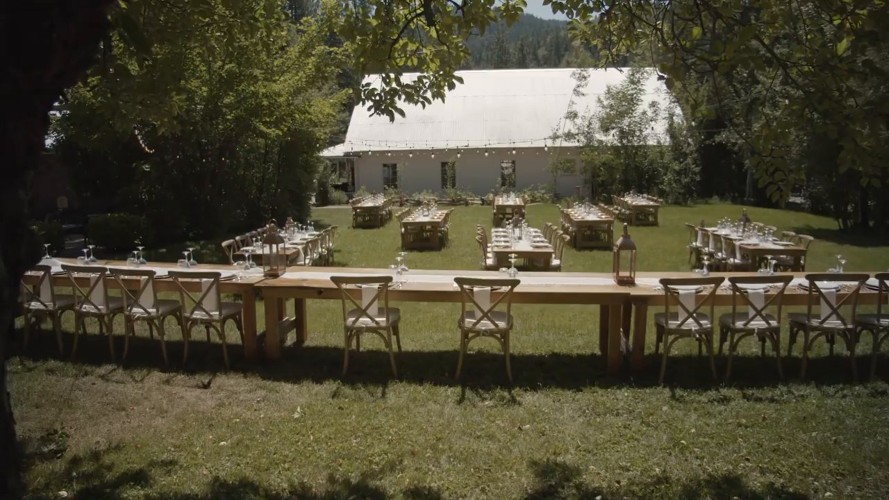 Long wooden reception tables set on the lawn in front of the white house.